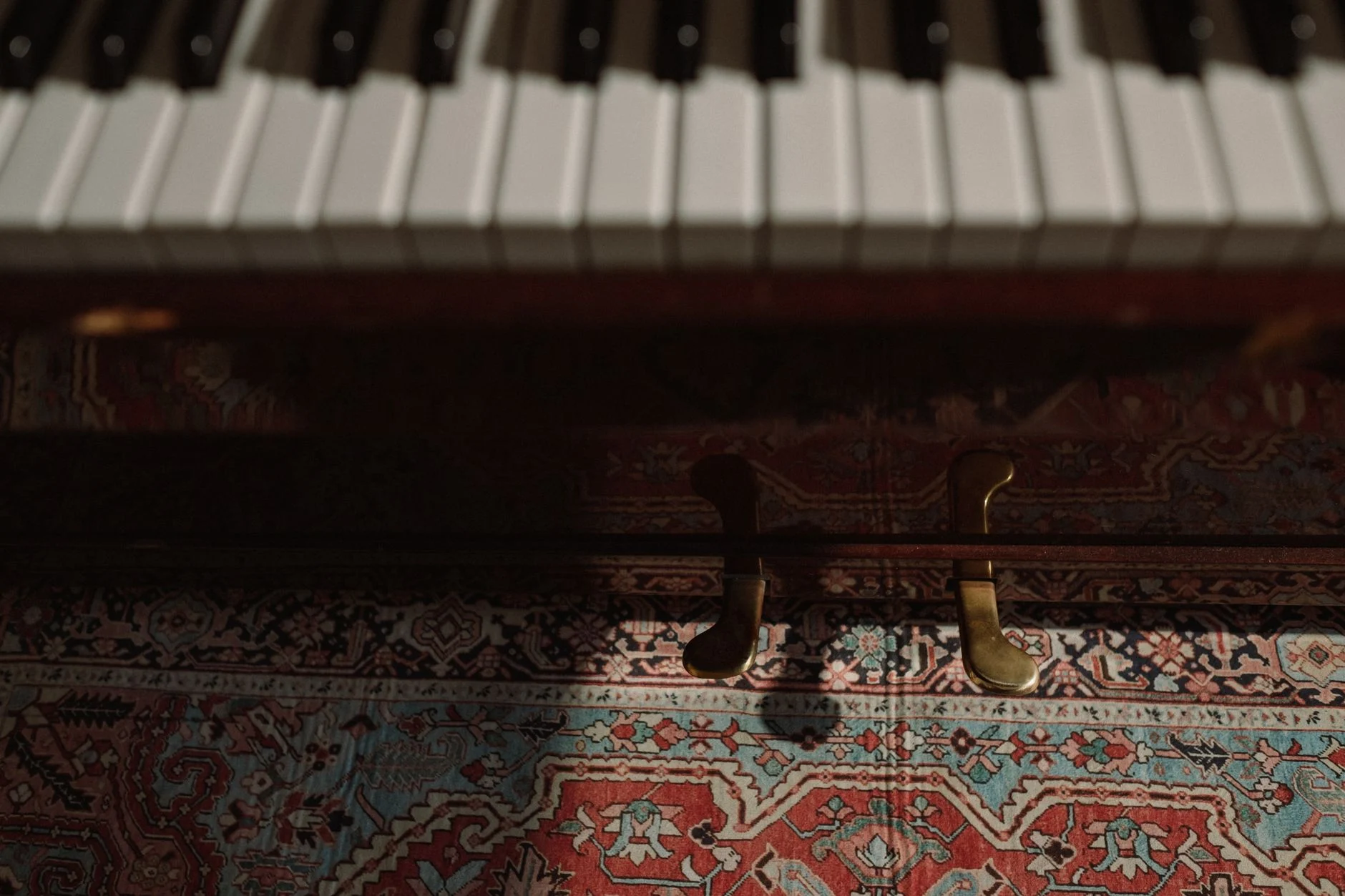 Artistic close-up of piano keys and pedals over vibrant patterned carpet in low light — an editorial image for "Bohemian Rhapsody: Structure, Production, and Lasting Influence."
