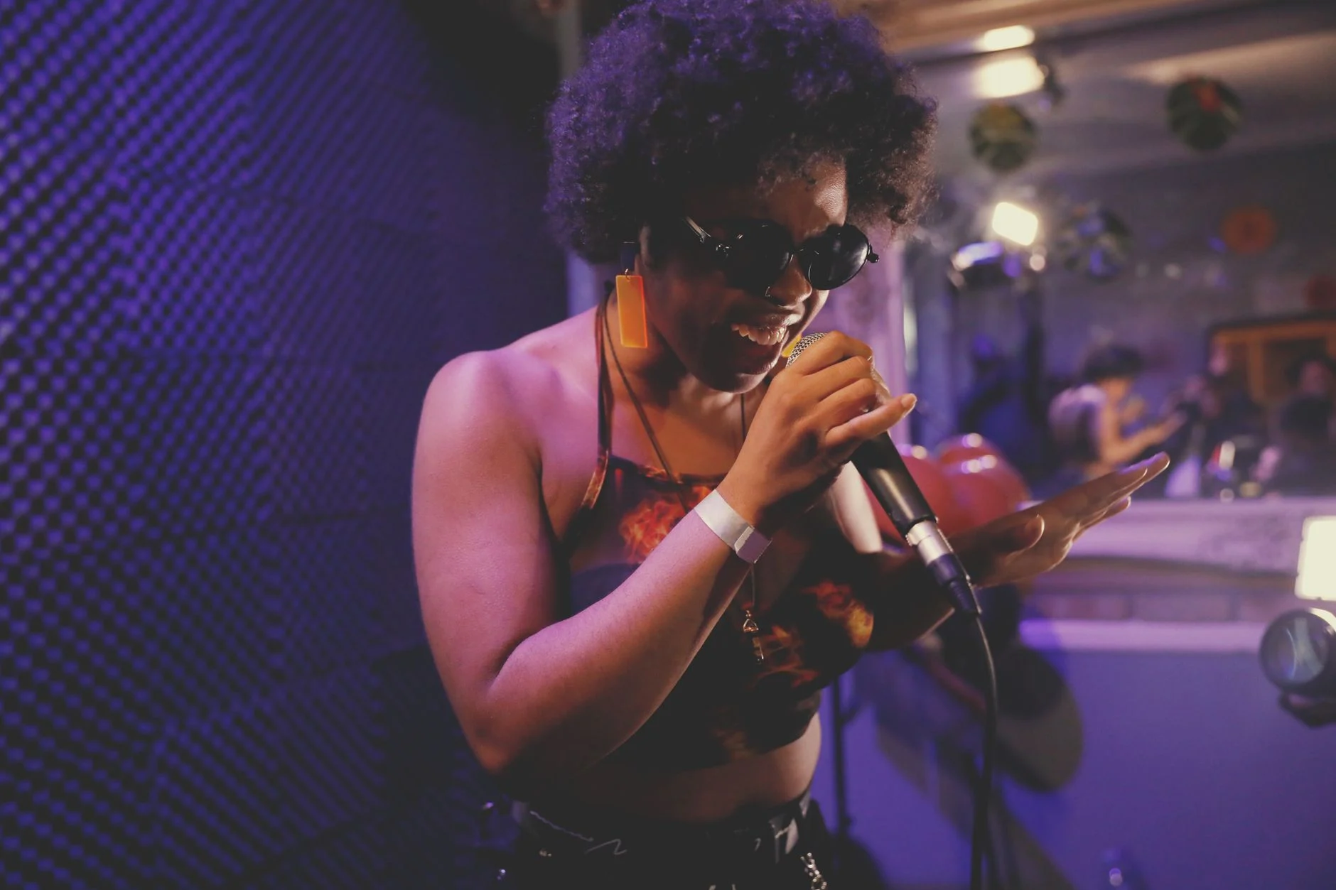 Female singer with afro hair energetically performing on stage with a microphone in a London nightclub — an editorial image for "The British Blues Boom and Its Influence on Rock."