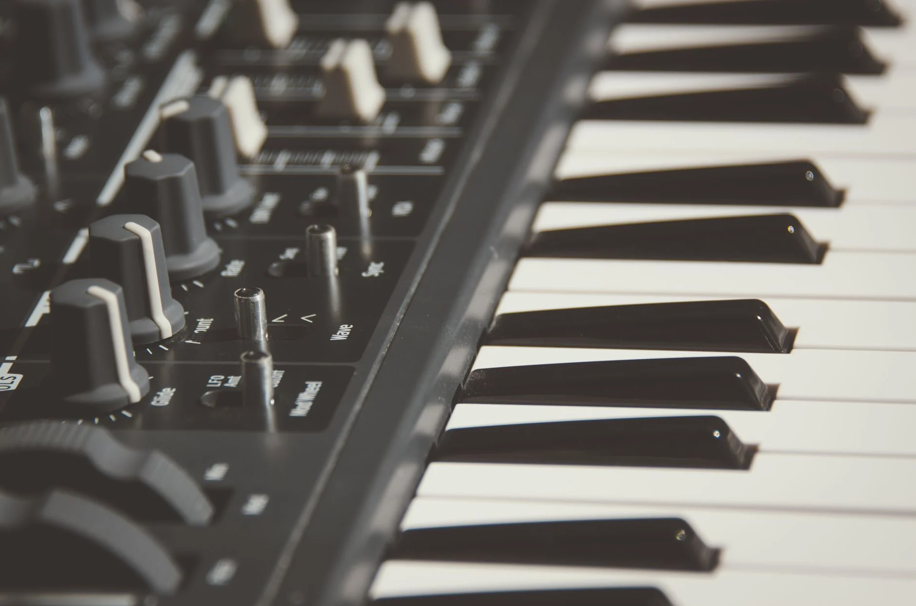 Detailed view of an electronic keyboard and its control knobs, highlighting modern musical equipment — an editorial image for "The Evolution of Electronic Dance Music."