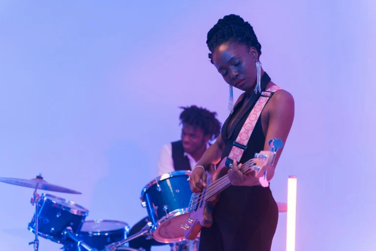 Two musicians in a vibrant indoor setting, playing bass guitar and drums passionately — an editorial image for "The Evolution of Funk and Its Rhythmic Legacy."
