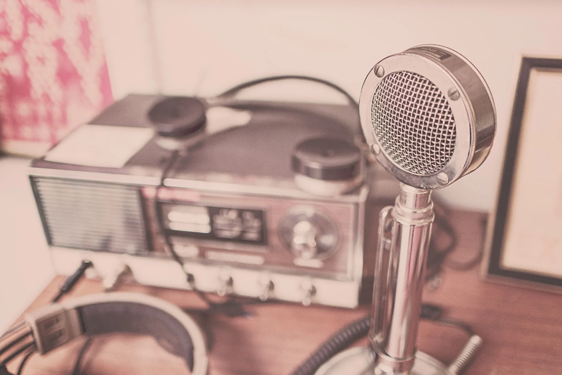 A classic vintage microphone and radio set with headphones displayed on a wooden table — an editorial image for "How Girl Groups Shaped the Sound of Early 1960s Pop."