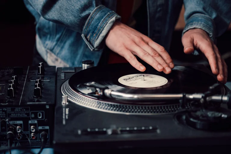 DJ mixing vinyl records on a turntable, creating live music with a sound mixer — an editorial image for "How Hip-Hop Grew from a Local Culture into a Global Movement."