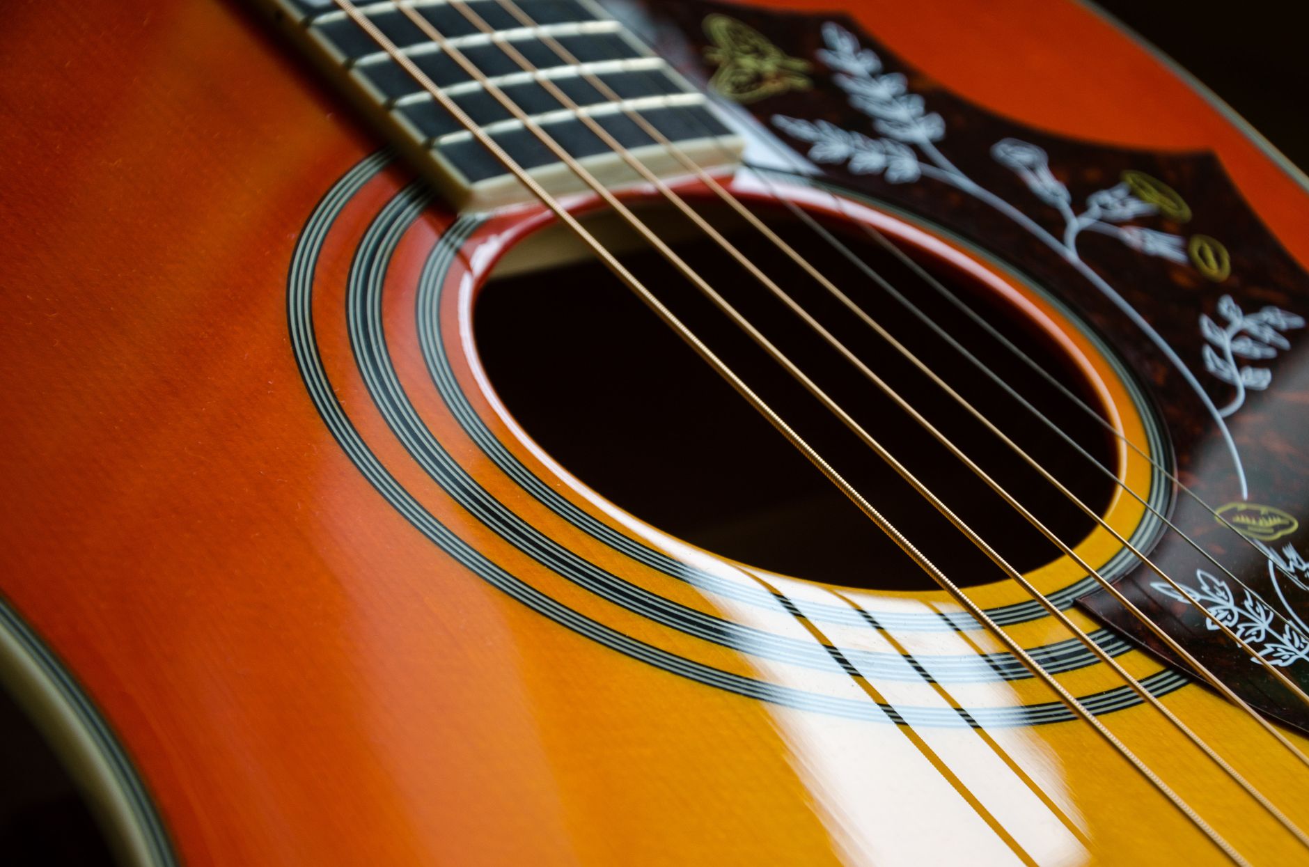 Detailed view of an acoustic guitar's strings and sound hole with intricate design — an editorial image for "How the Blues Shaped Modern Popular Music."