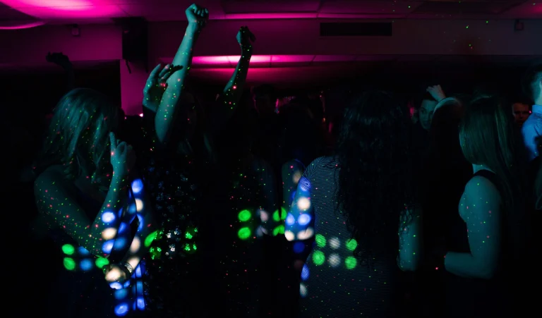 Energetic nightclub scene with people dancing under colorful neon lights. Perfect for nightlife themes — an editorial image for "Madonna and the Evolution of the Modern Pop Star."