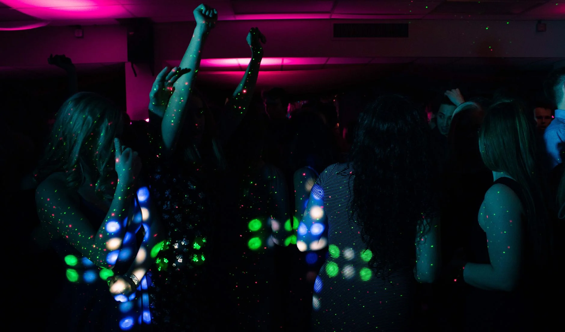 Energetic nightclub scene with people dancing under colorful neon lights. Perfect for nightlife themes — an editorial image for "Madonna and the Evolution of the Modern Pop Star."