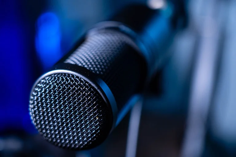 Detailed close-up of a professional studio microphone with a blurred blue background — an editorial image for "The Miseducation of Lauryn Hill and the Sound of 1990s Hip-Hop Soul."