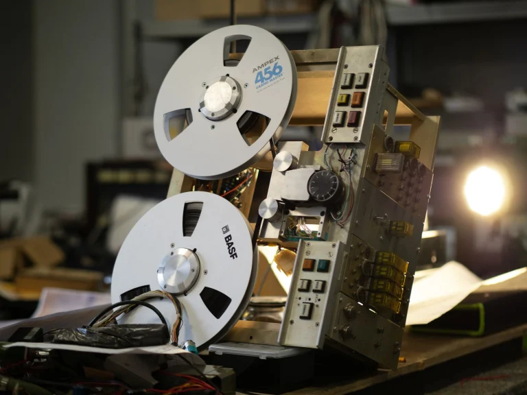 Close-up of a classic reel-to-reel tape recorder in a vintage recording studio setting — an editorial image for "How Multitrack Recording Technology Changed Songwriting."