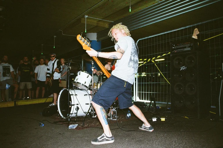Dynamic live music performance with a band playing in an urban parking lot — an editorial image for "How Punk Rock Challenged the Music Industry."