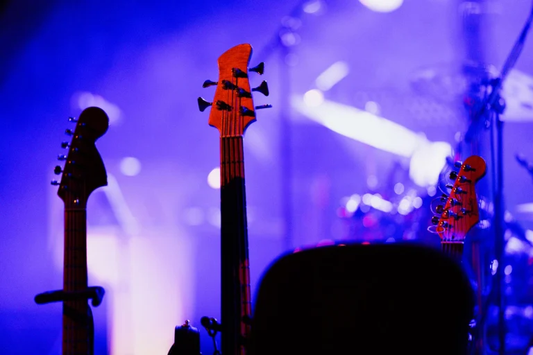 Electric guitars on stage under colorful concert lights, capturing the vibrant music atmosphere — an editorial image for "Purple Rain: How Music, Film, and Performance Came Together."