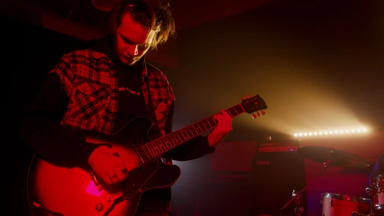Guitarist playing electric guitar on stage with moody lighting — an editorial image for "Smells Like Teen Spirit and the Sound of a Generational Shift."