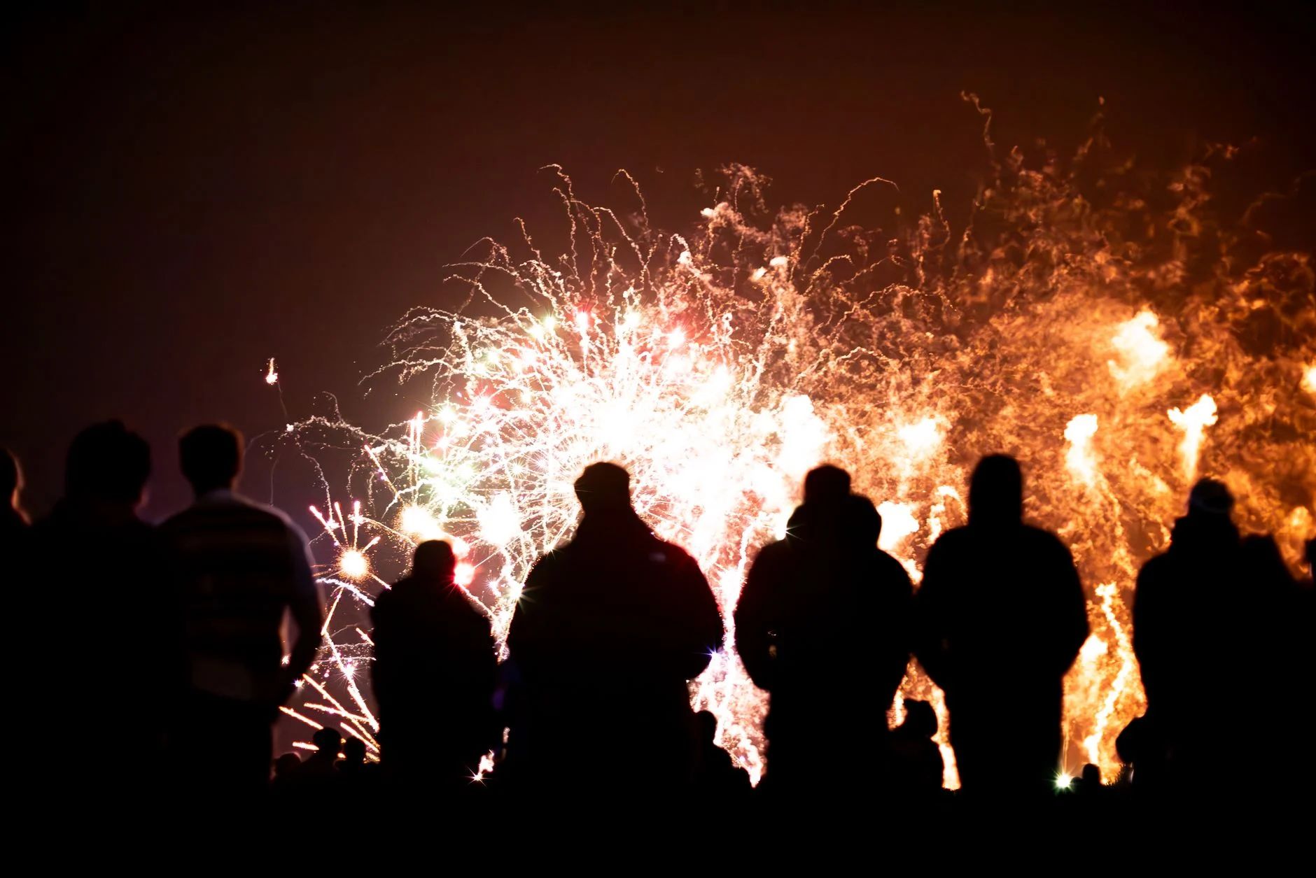 Silhouetted crowd watching a vibrant fireworks display in the night sky, capturing the essence of celebration and wonder — an editorial image for "Woodstock and the Rise of the Music Festival."